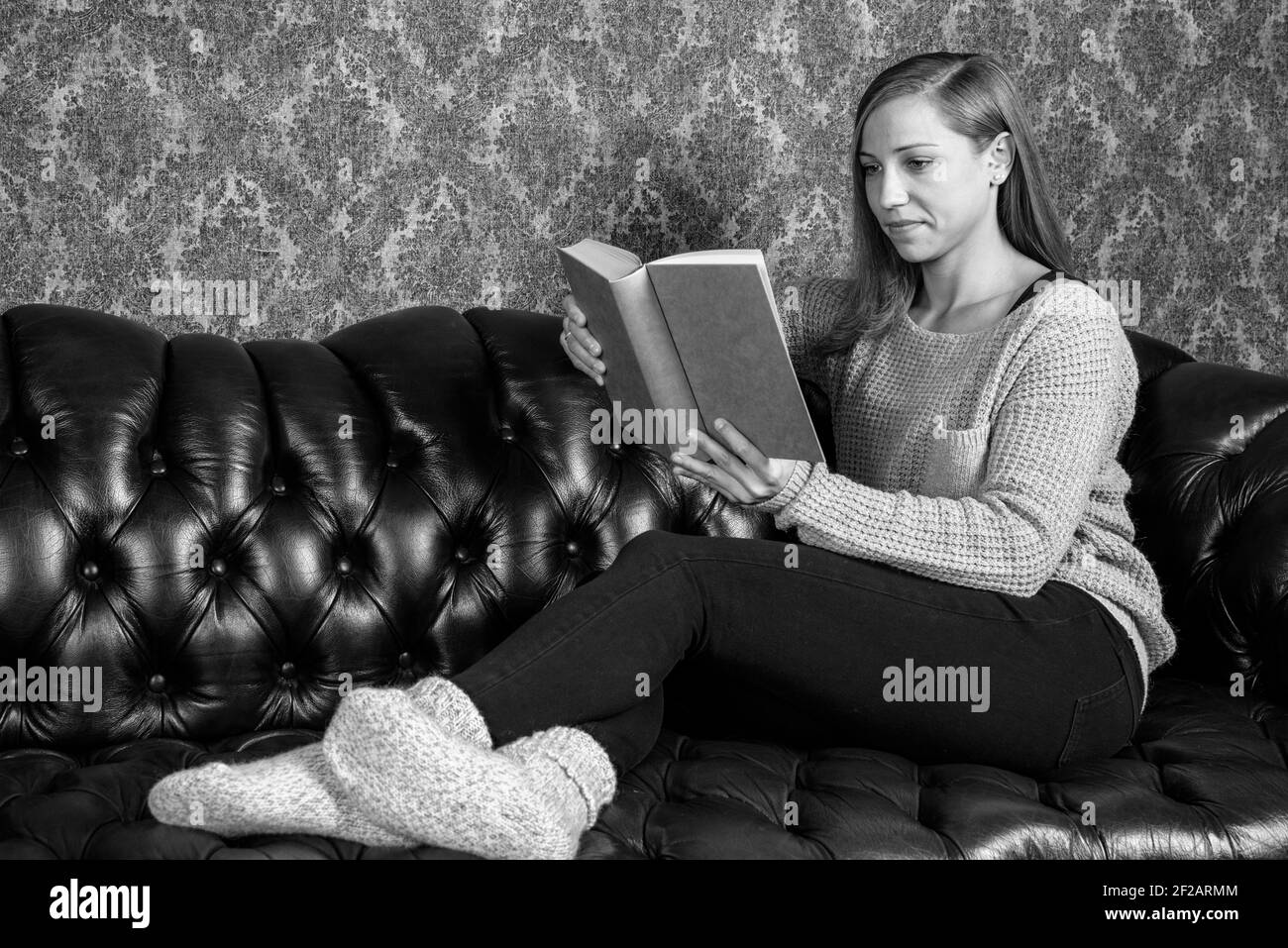 Relaxed girl reads a book in bookstore in black and white Stock Photo