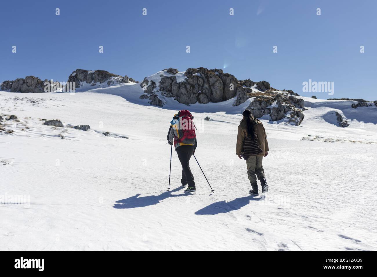 A back view of two hikers climbing a snowy mountain Stock Photo - Alamy