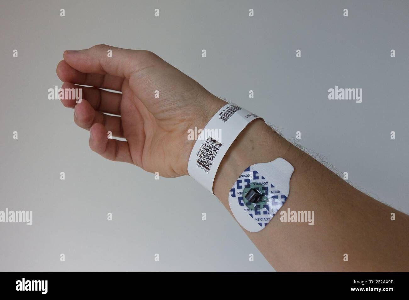 Hospital tag on wrist with ECG pad, white Caucasian, white, pale skin, id tag, hospital tag, ecg pad, palm of the hand, right hand, fingers, wrist Stock Photo