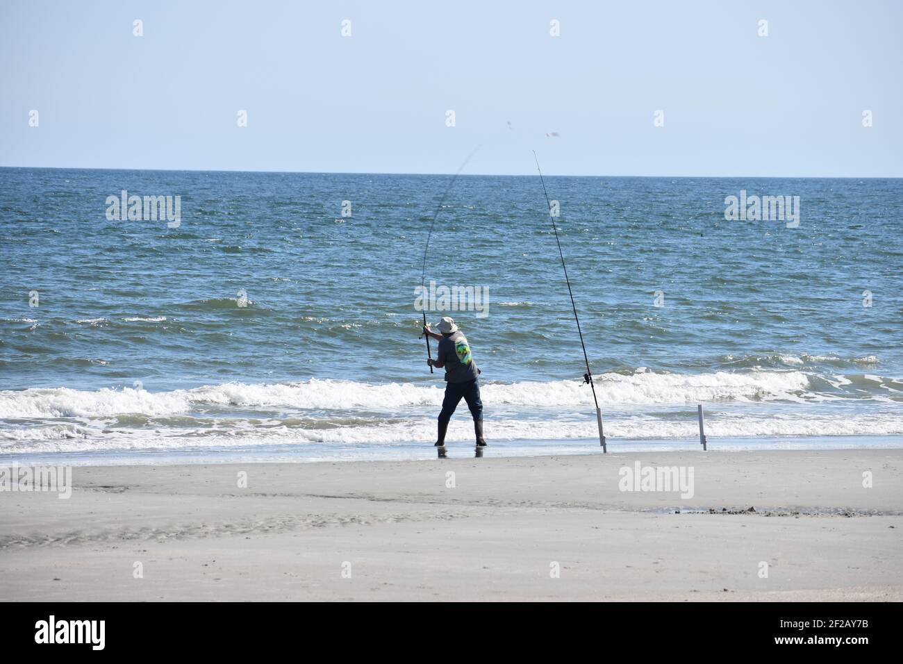 Myrtle Beach spring 2021 surf fisherman casting his fishing line into the Atlantic Ocean Stock Photo