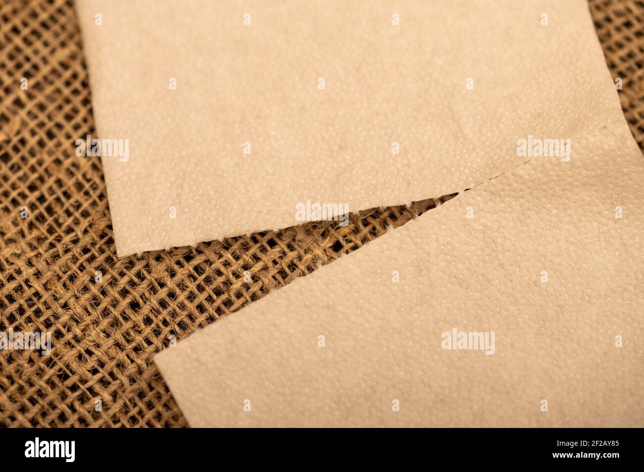 Paper napkins on a background of homespun fabric with a rough texture. Close-up, selective focus. Stock Photo