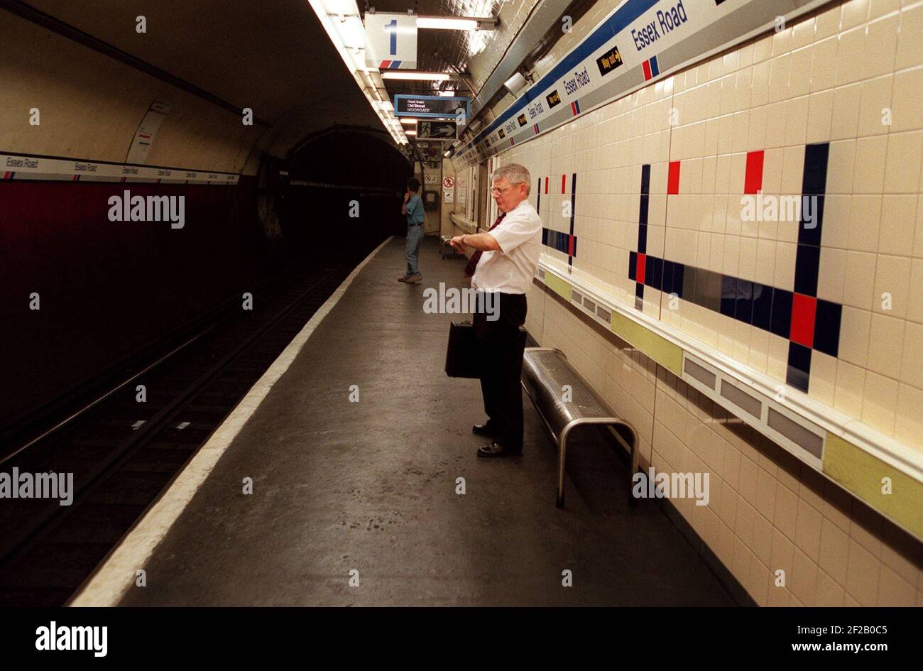 ESSEX ROAD STATION IS REGARDED AS PART OF THE UNDERGROUND. PASSENGER CHECKS HIS WATCH, WHILST WAITING ON THE PLATFORM Stock Photo