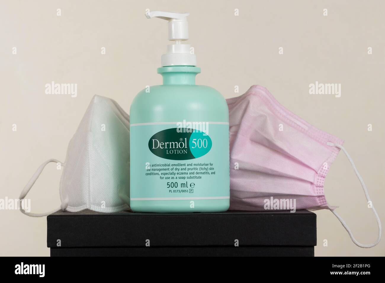 London, UK. 11 March 2021. A bottle of Dermol 500, an antimicrobial soap  substitute which also contains an emollient to help keep skin hydrated,  shown next to facemasks. It has been reported