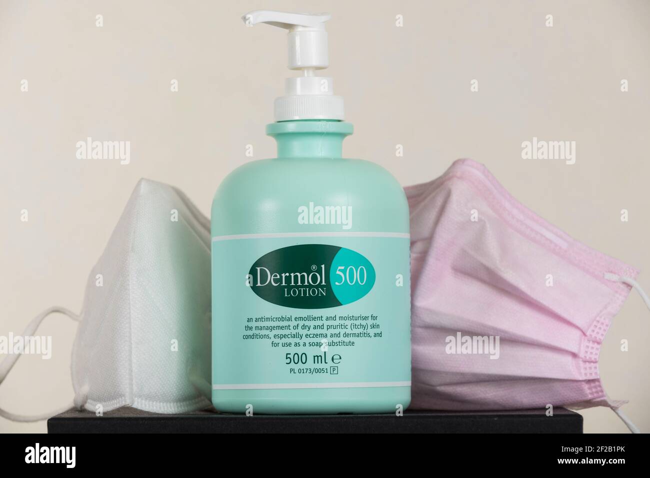 London, UK. 11 March 2021. A bottle of Dermol 500, an antimicrobial soap  substitute which also contains an emollient to help keep skin hydrated,  shown next to facemasks. It has been reported
