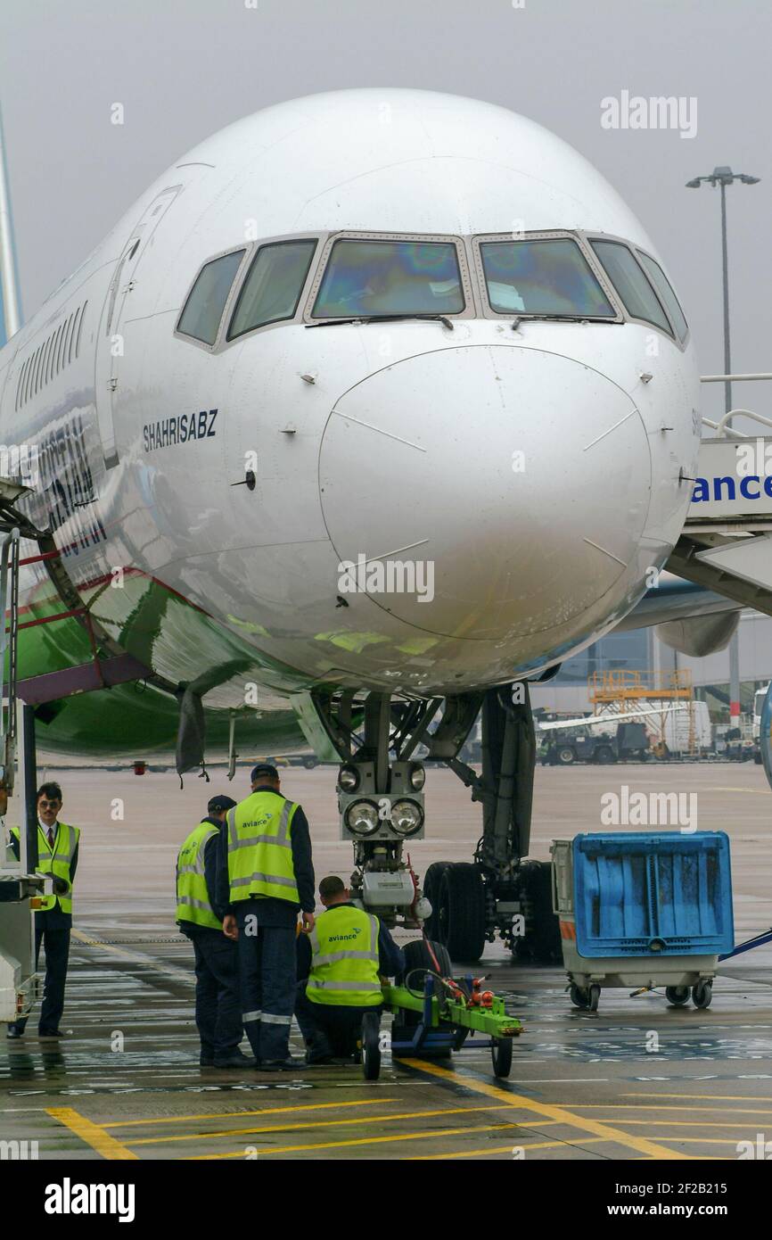 Airport ground crew working on an Uzbekistan Airways Boeing 757 passenger plane in the apron area at Birmingham Airport, England. Stock Photo