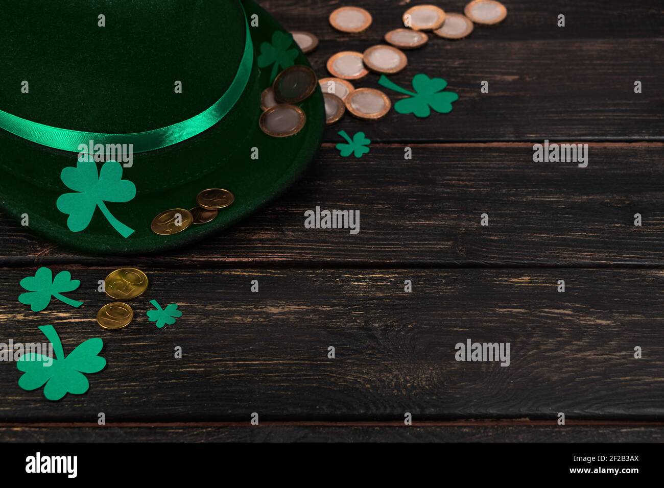 Leprechaun hat and shamrock clover leaves on brown wooden background. Happy St. Patrick's Day. Place for your text. Stock Photo