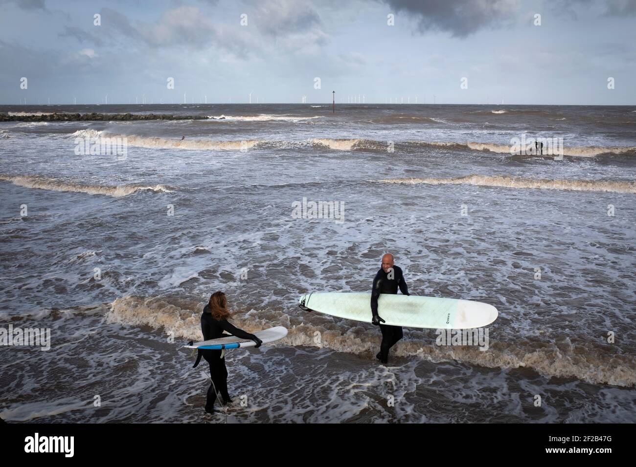 A group of surfers in the sea in the mouth of the river Mersey. High tides and a storm which swept across the United Kingdom brought favourable conditions for surfing in Leasowe Bay, Merseyside on 11 March, 2021. Stock Photo