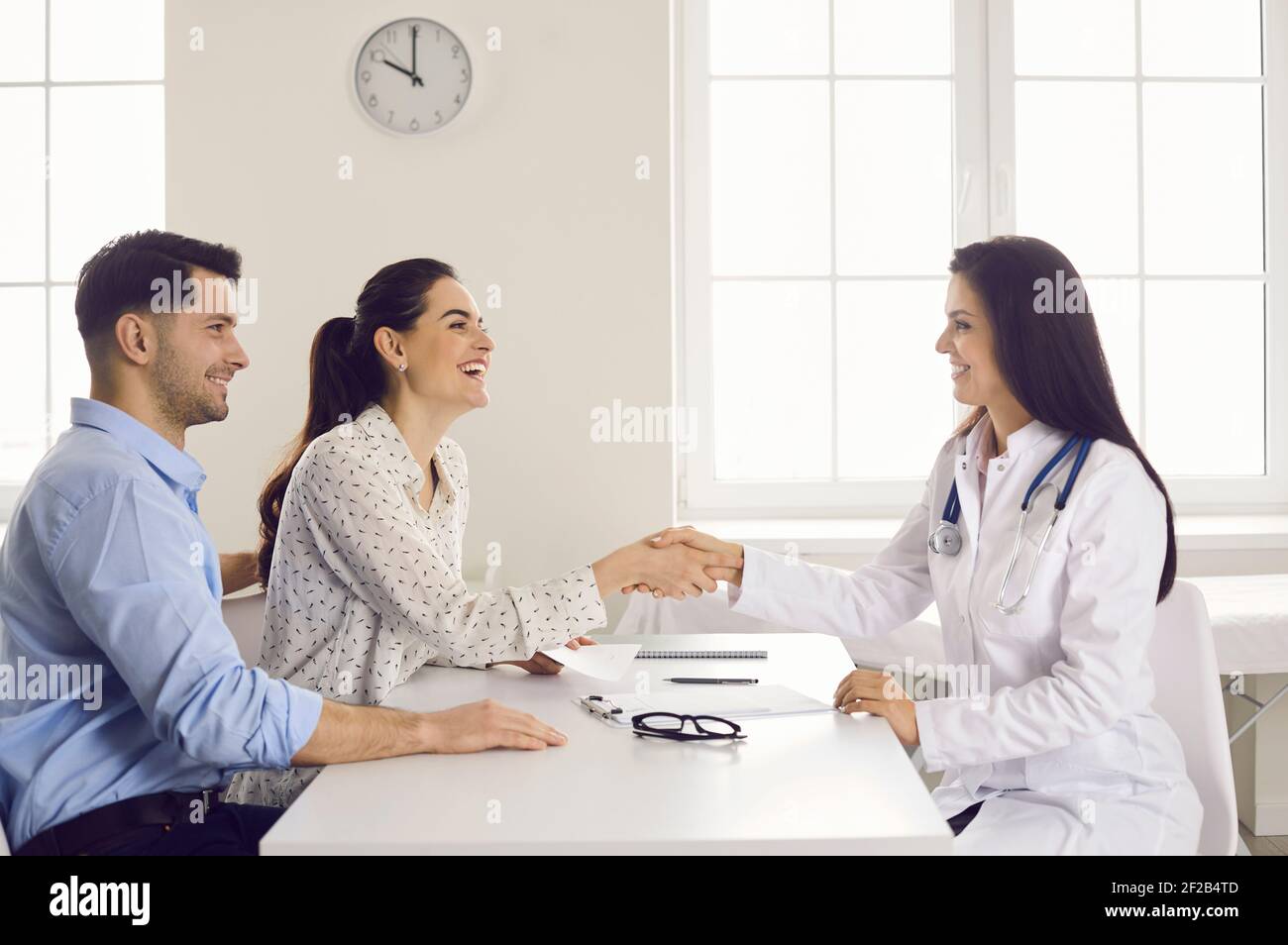 Happy woman patient giving gratitude handshake to doctor during appointment Stock Photo