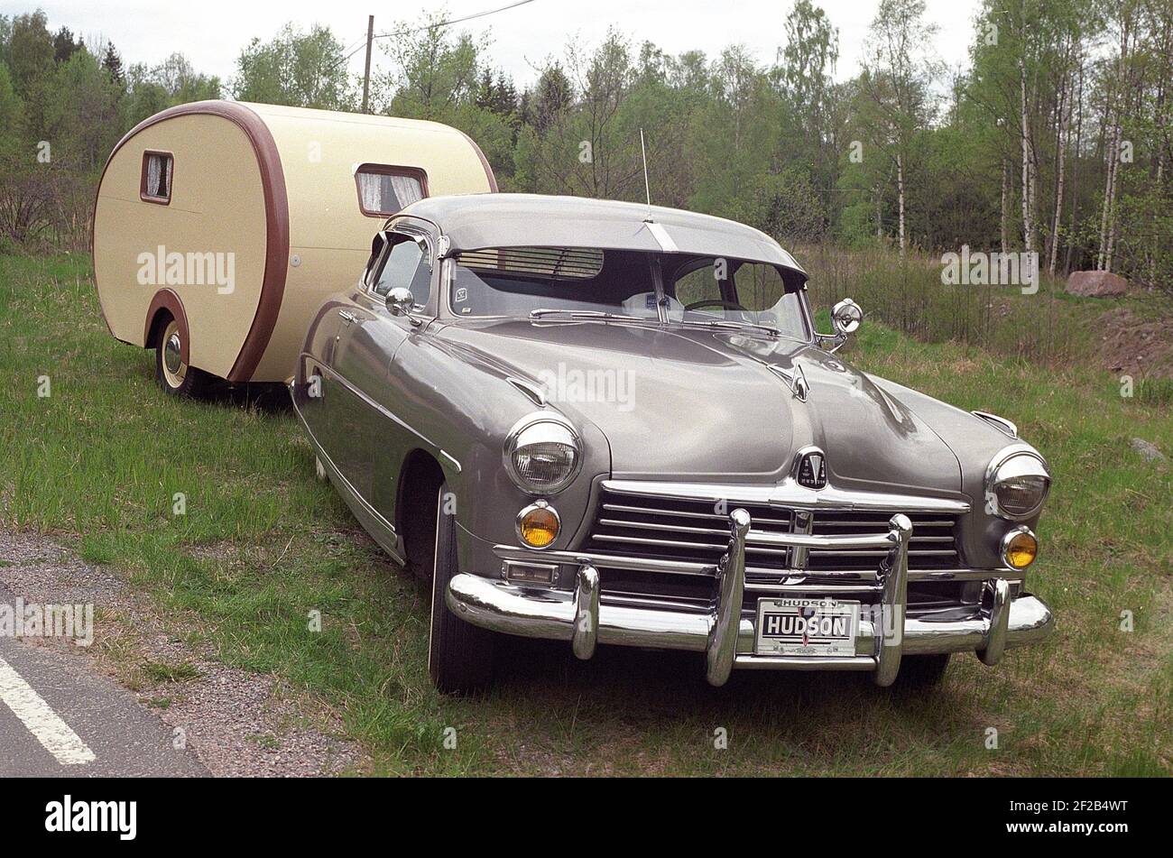 Vintage camping. An american 1950s car with a vintage looking caravan trailer photographed on the side of the road. Stock Photo