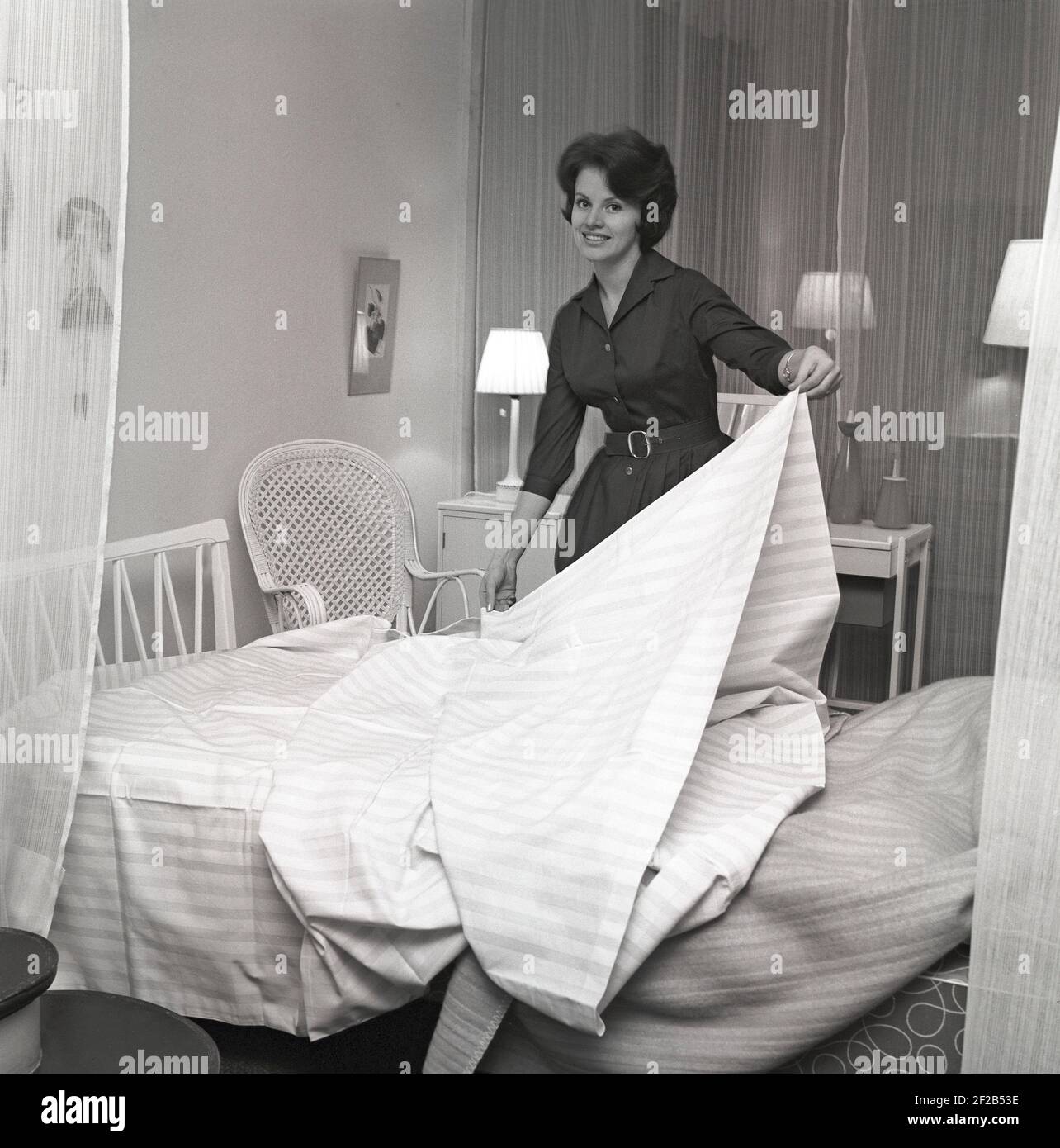 In the 1960s. A woman is making her bed with fresh sheets. Sweden 1960 ref CS12-5 Stock Photo