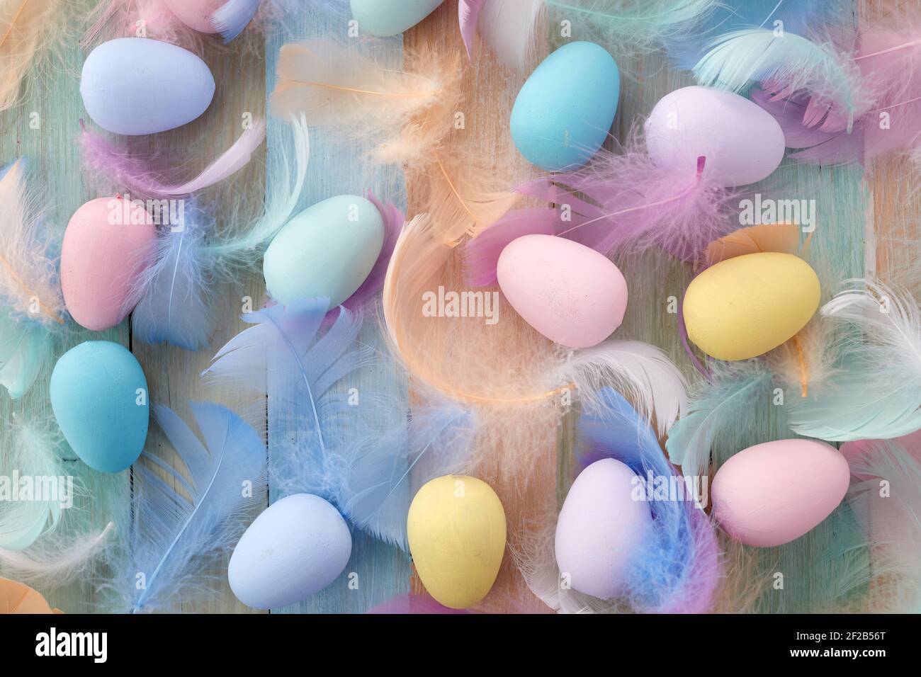 Happy easter concept. Colorful Easter eggs and feathers on wooden background. Flat lay. Stock Photo
