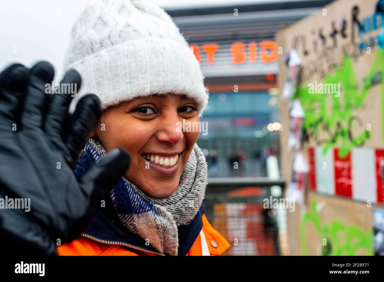 Berlin, Germany. Young Girl attracting attention to East Side Mall shopping center, by standing outside in cold and rainy weather holding a sign, directing, potential customers to commercial shops and stores. Stock Photo