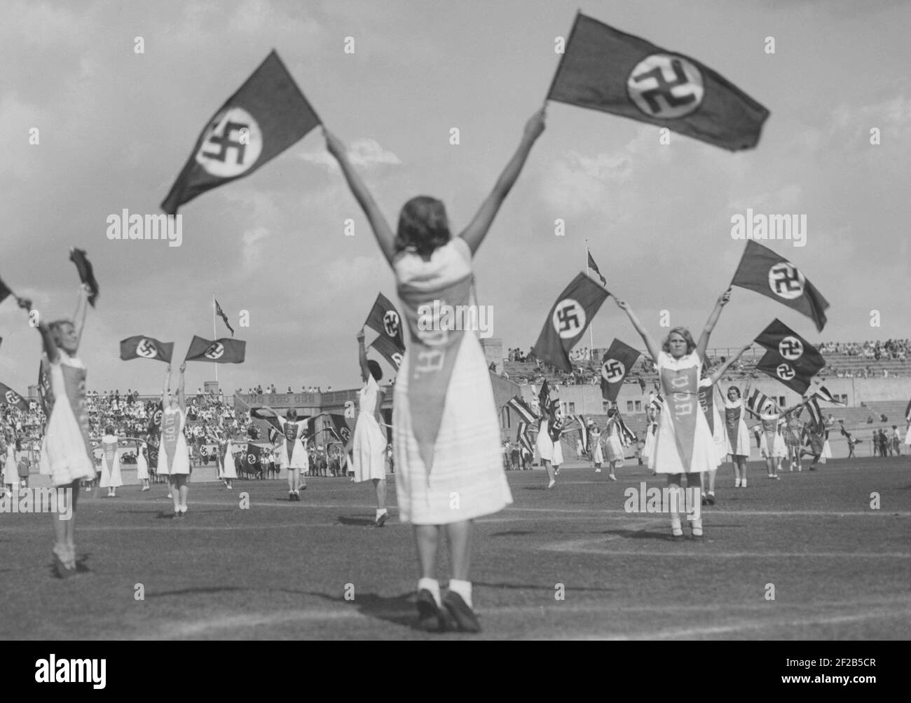 Germany in the 1930s. German schoolchildren practice a routine on Berlins sportsarena Deutsches Stadion. Using the national socialist flag is part of the routine. The flag became Nazi Germanys only offical flag from 1935. Stock Photo