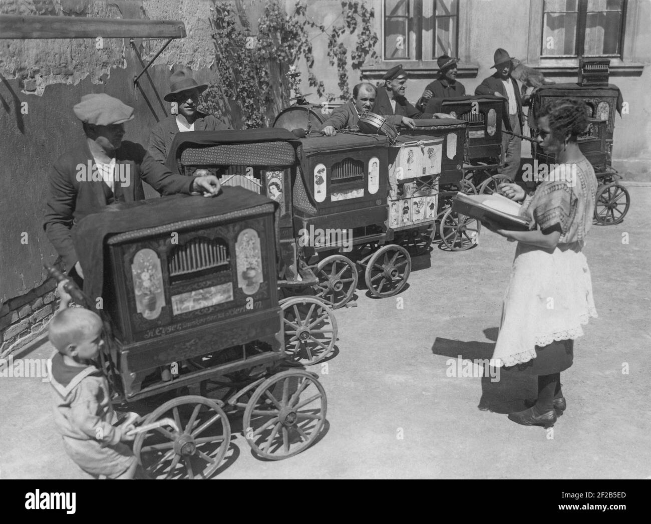 Organ grinders of the 1930s. A group of several such together in the street all different models of the traditional manually operated musical machine. The organ grinder played in the street and people gave some money to them if they liked it. 1930s Stock Photo