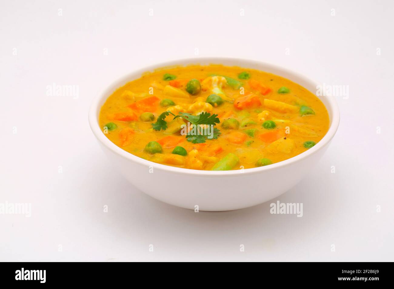 Mixed veg curry or kurma  tasty indian dish made of different vegetables like cauliflower, carrot, potato, green peas and garnished with onion pieces Stock Photo