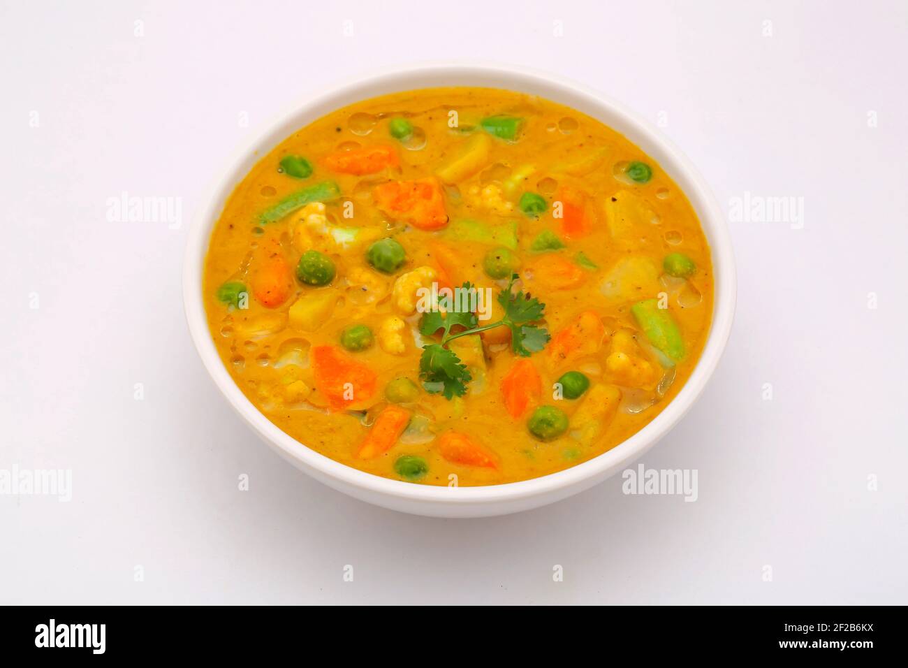 Mixed veg curry or kurma  tasty indian dish made of different vegetables like cauliflower, carrot, potato, green peas and garnished with onion pieces Stock Photo