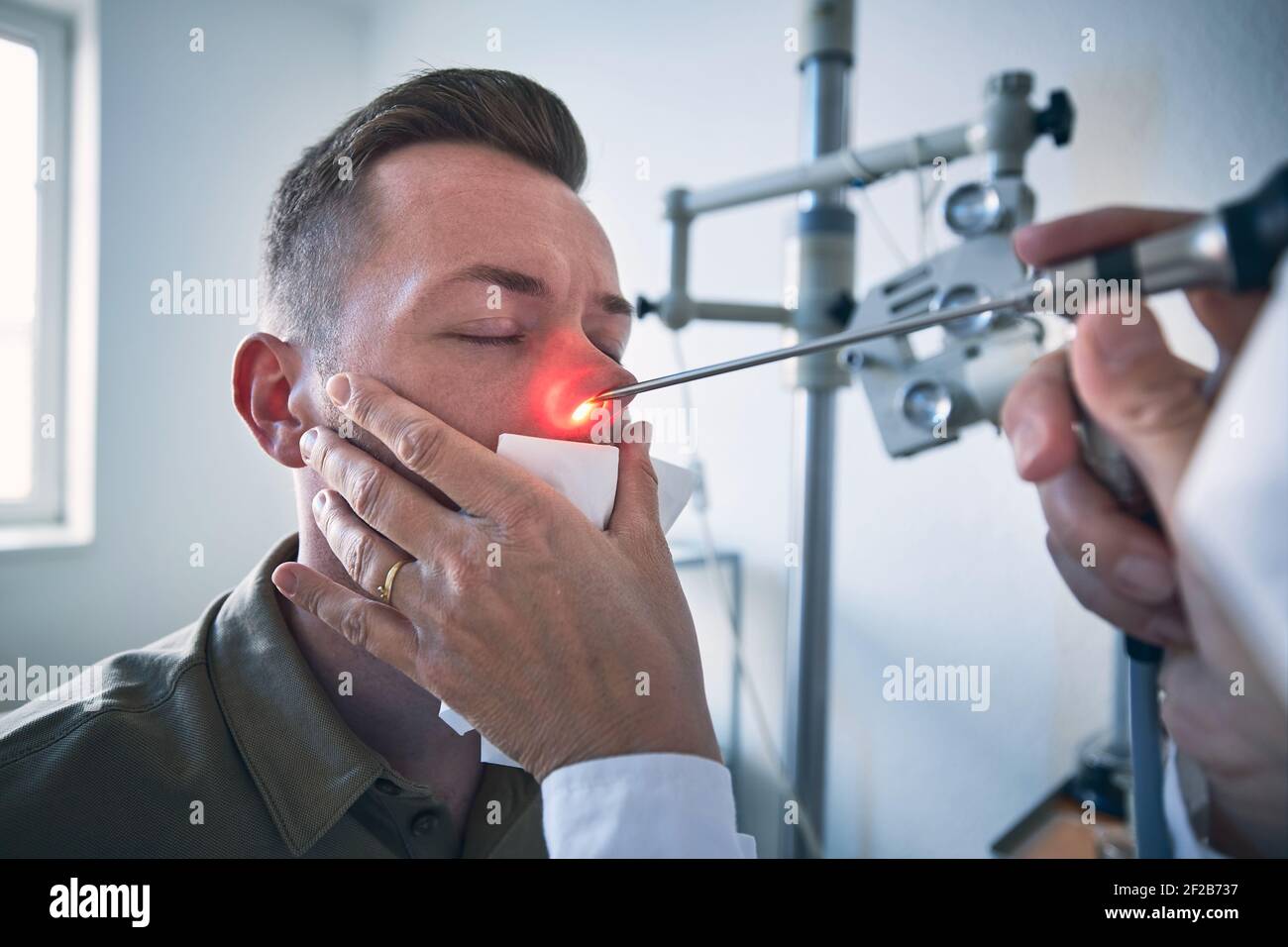 Patient at ENT clinic. Specialist doctor - Otolaryngologist doing nose examination of young man. Stock Photo