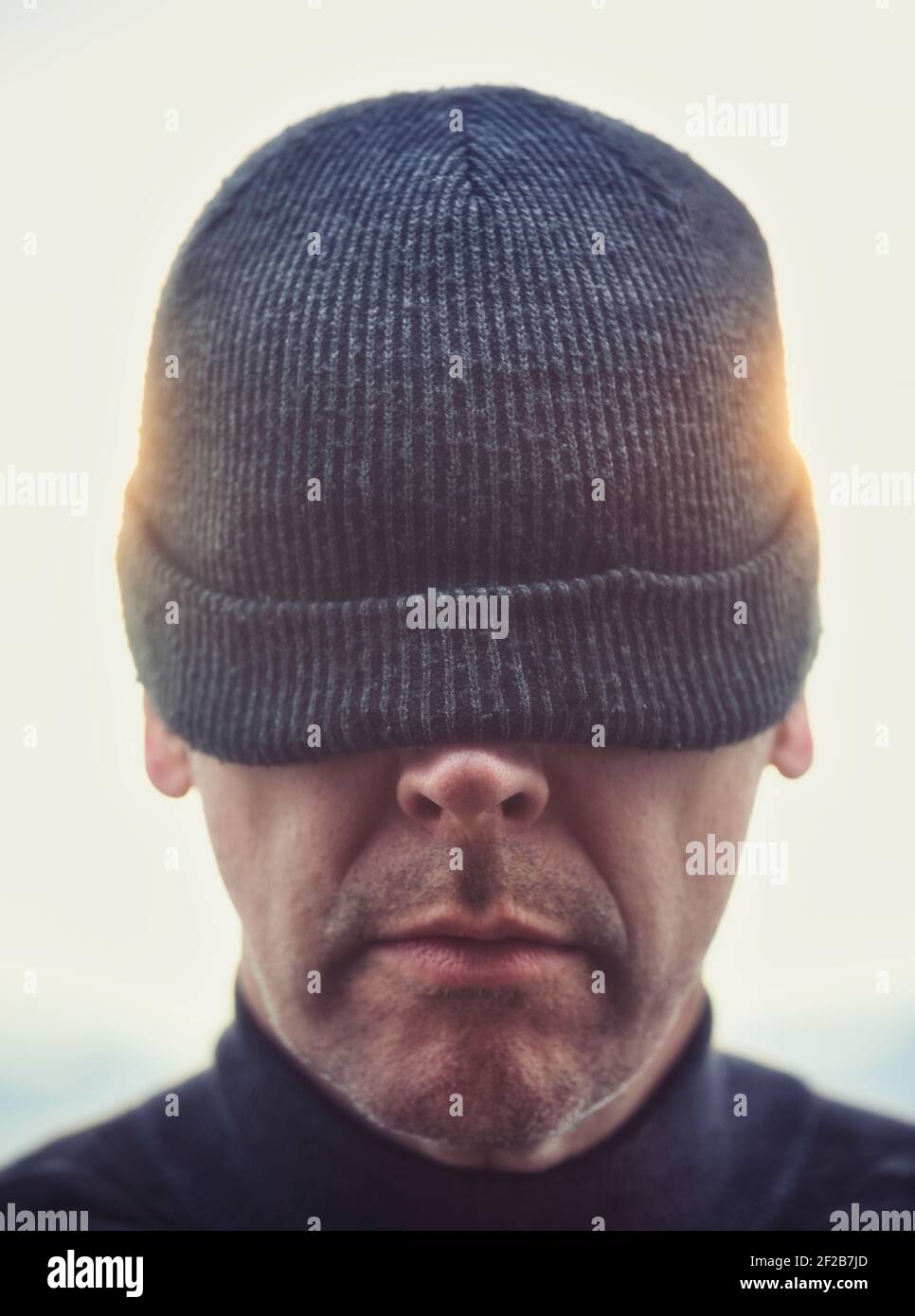 Close up of mid adult man wearing beanie pulled down to cover his eyes. Concept of intrigue, curiosity, hiding Stock Photo