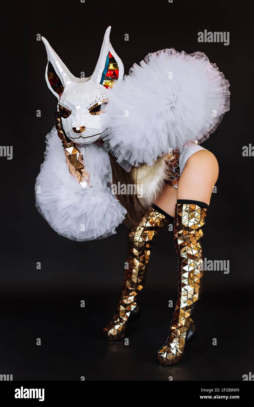 Beautiful sexy woman in rabbit bunny mask and carnival costume posing on dark background. Halloween, masquerade or costume party concept. Stock Photo