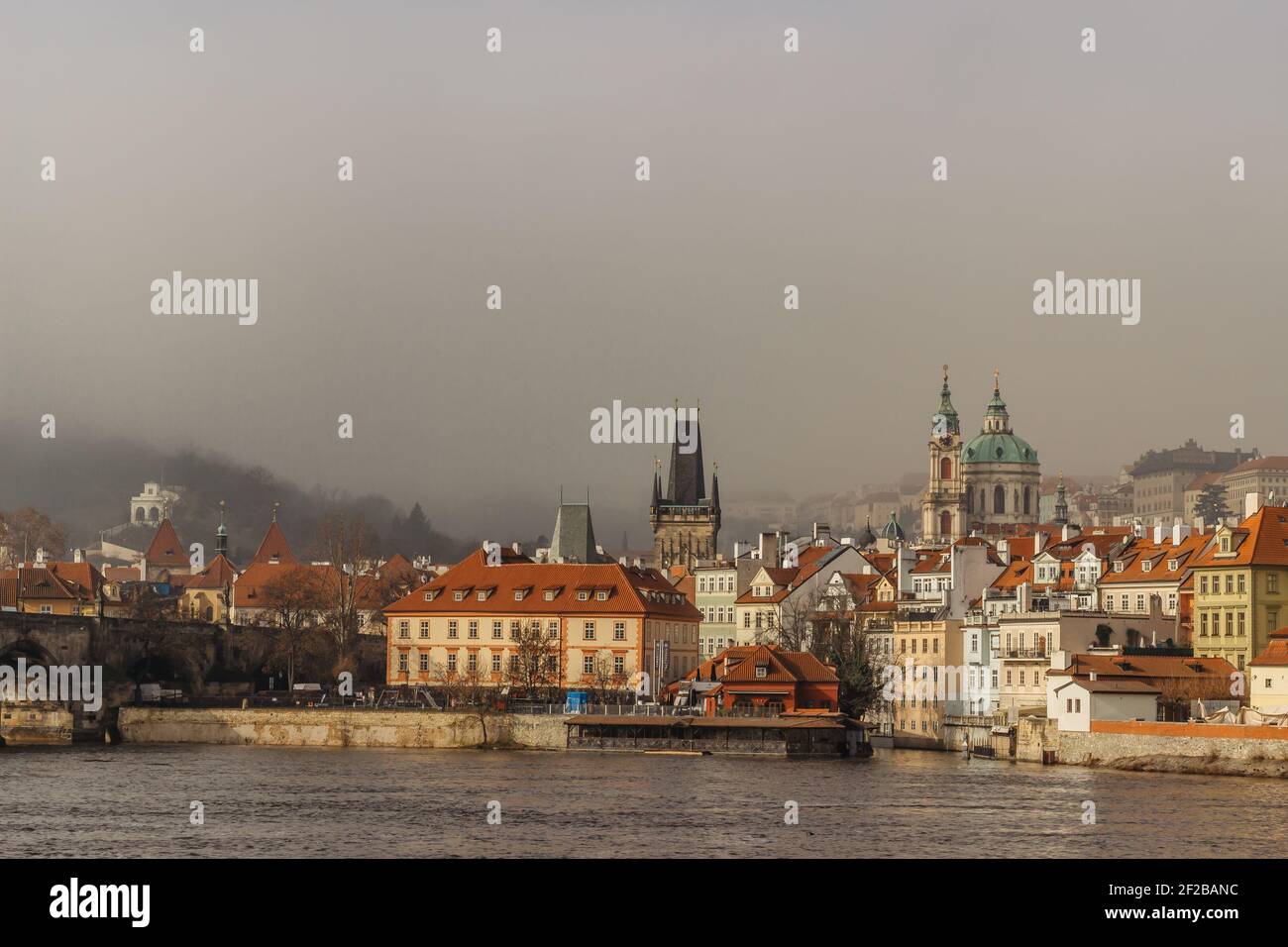 Postcard view of Lesser Town in mist from Charles Bridge,Czech republic.Famous tourist destination.Prague panorama.Foggy morning in city.Amazing Stock Photo