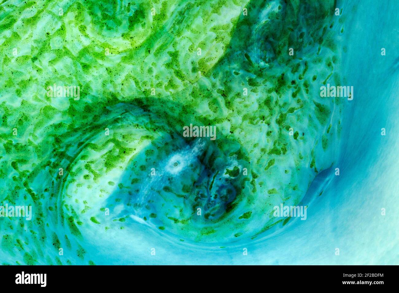 Abstract mottled and speckled green shapes spiral into cool blue swirls in  this detail view of a creation in contemporary French hand-blown art glass,  a fruit bowl created by master 'souffleur de