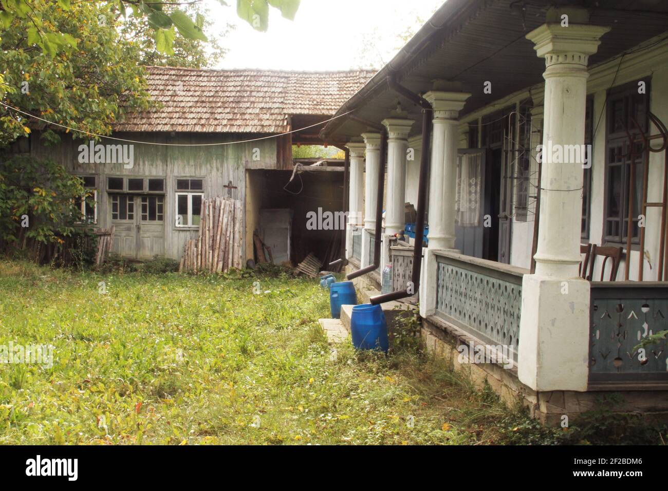 Courtyard in Vrancea, Romania.  Old traditional house and barn. Rain water saved in containers. Stock Photo
