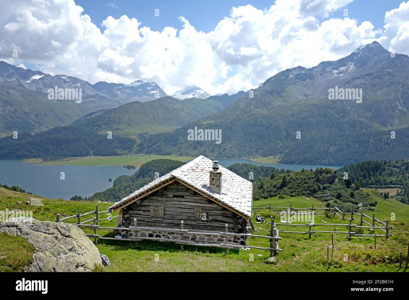 mountain cabin with a mountain lake in the background, with a panoramic view of the Engadin valley, in Switzerland. Stock Photo
