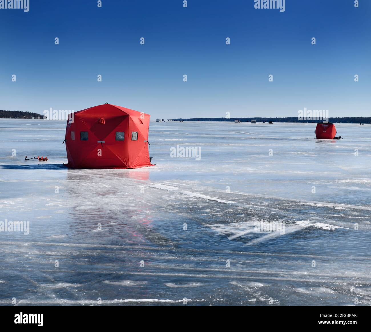 Barrie, Ontario, Canada - March 7, 2021: Red ice fishing tent with drill on frozen blue ice of Kempenfelt Bay on Lake Simcoe in winter Stock Photo