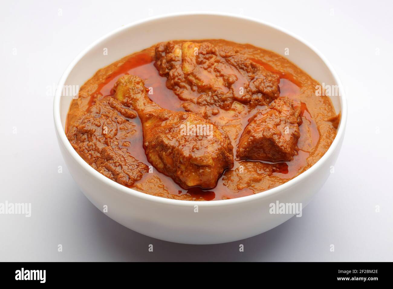 Chicken curry or masala , spicy chicken curry made using fried coconut in traditional way,arranged in a white ceramic bowl with white background,isola Stock Photo