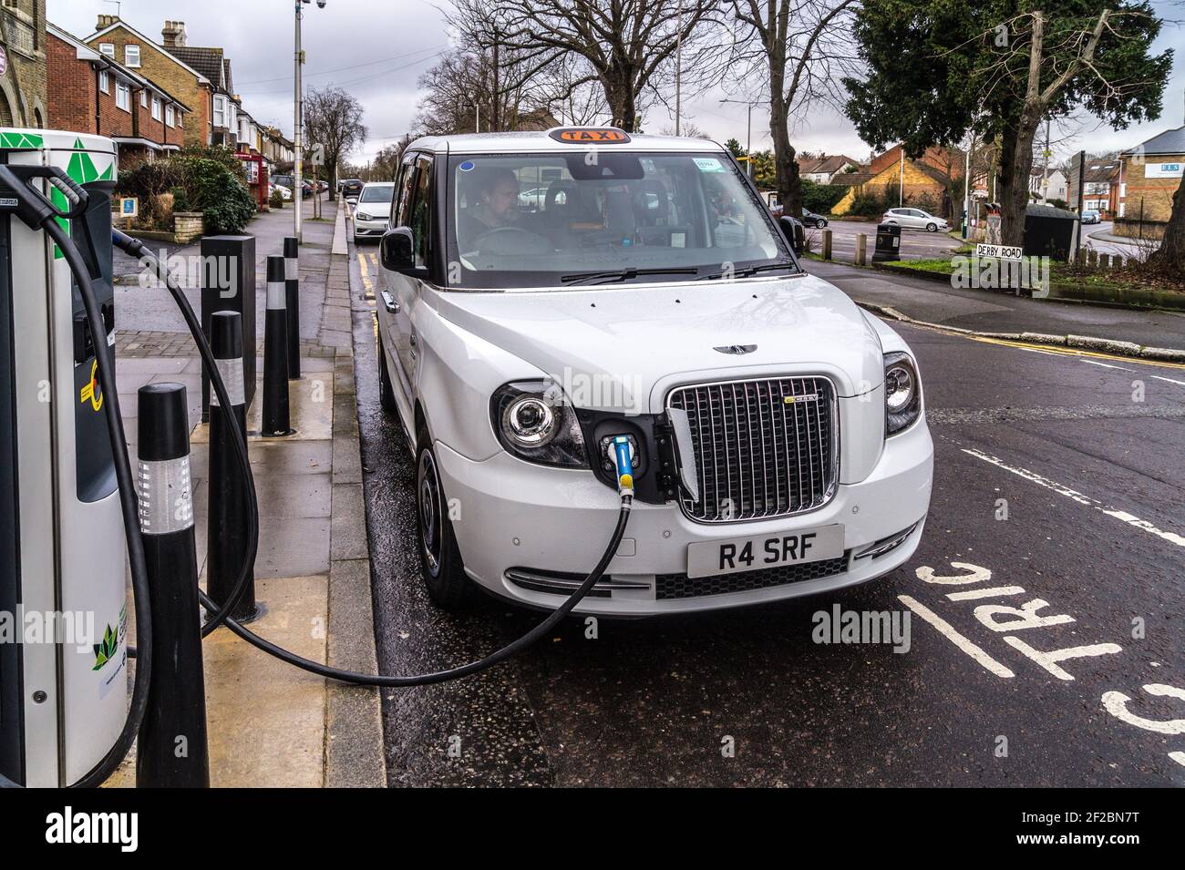 White LEVC TX taxi plugged into a Chargemaster charging station, South Woodford, London E18, England Stock Photo