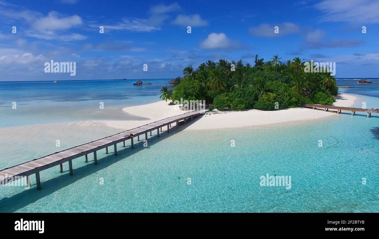 Tropical island in Maldives, aerial panoramic view. Beautiful paradise island with white sand, coco palm trees and crystal clear turquoise water. Stock Photo