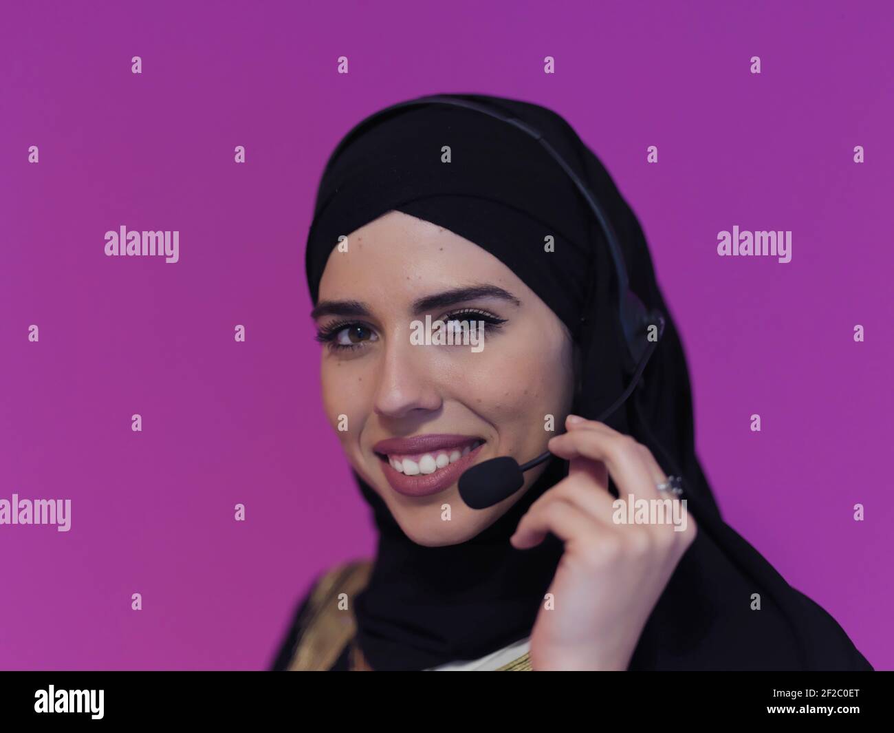 Portrait of young muslim woman with headphones working as call center ...