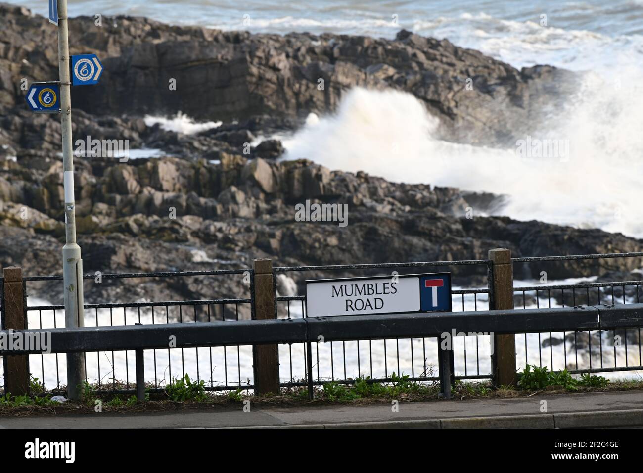Strong Winds and Storm Surf batter the coastline at Mumbles Head. Mumbles Road sign on verge. Stock Photo