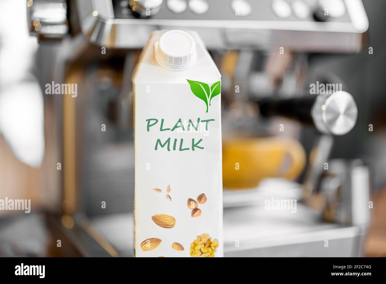 Packaging of vegetable milk near coffee machine. Organic nut dairy, alternative drink. Close up. Stock Photo