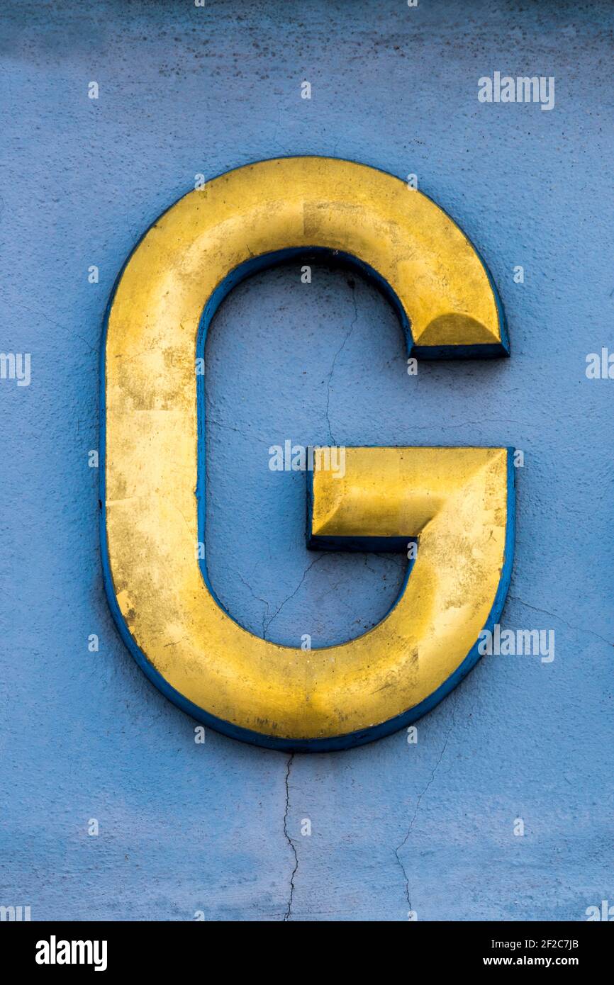 Golden letter G on a blue wall Stock Photo