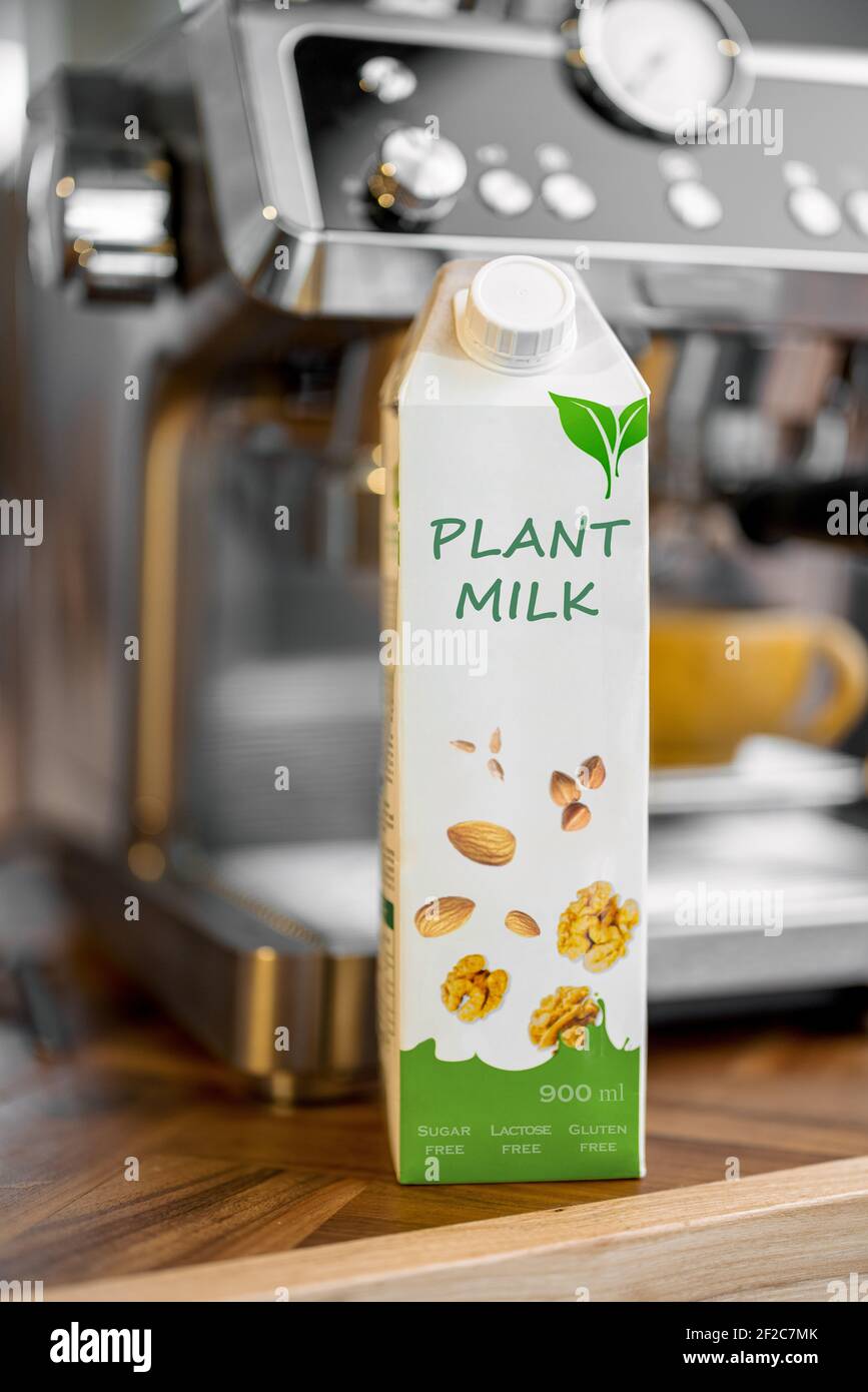 Packaging of vegetable milk near coffee machine. Organic nut dairy, alternative drink.  Stock Photo