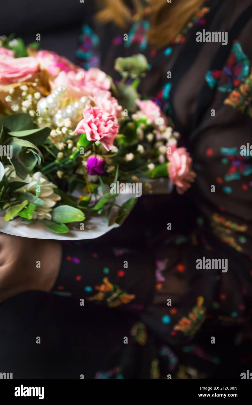 Defocus Florist woman holding a beautiful blossoming flowers bouquet in pink and green colors of roses, peony, myrtle, pistachio leaves. Woman get Stock Photo