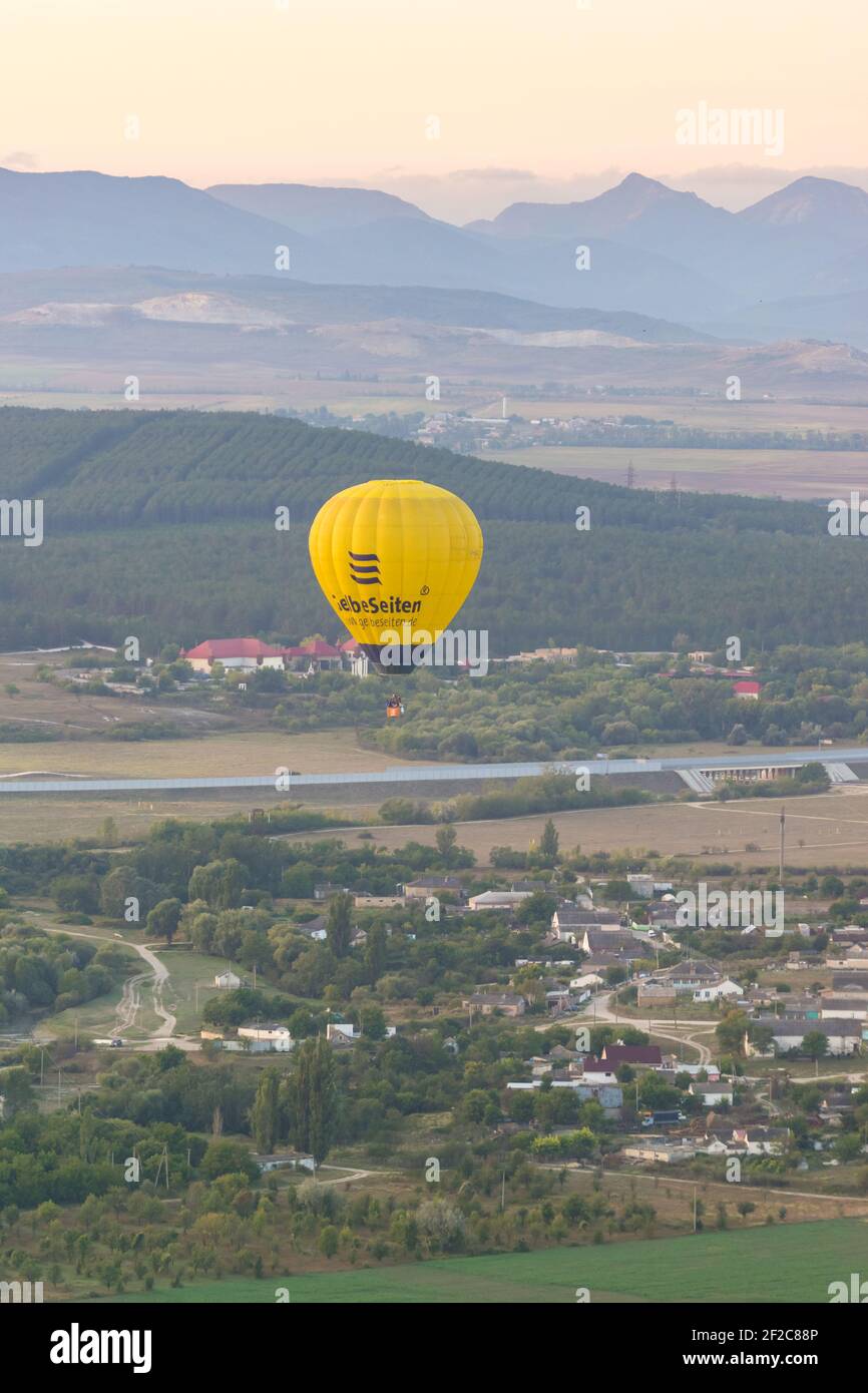 Russia, Crimea, Belogorsk September 19, 2020-A yellow balloon with the GelbeSeiten logo flies over the village of Belaya Skala at the foot of the moun Stock Photo