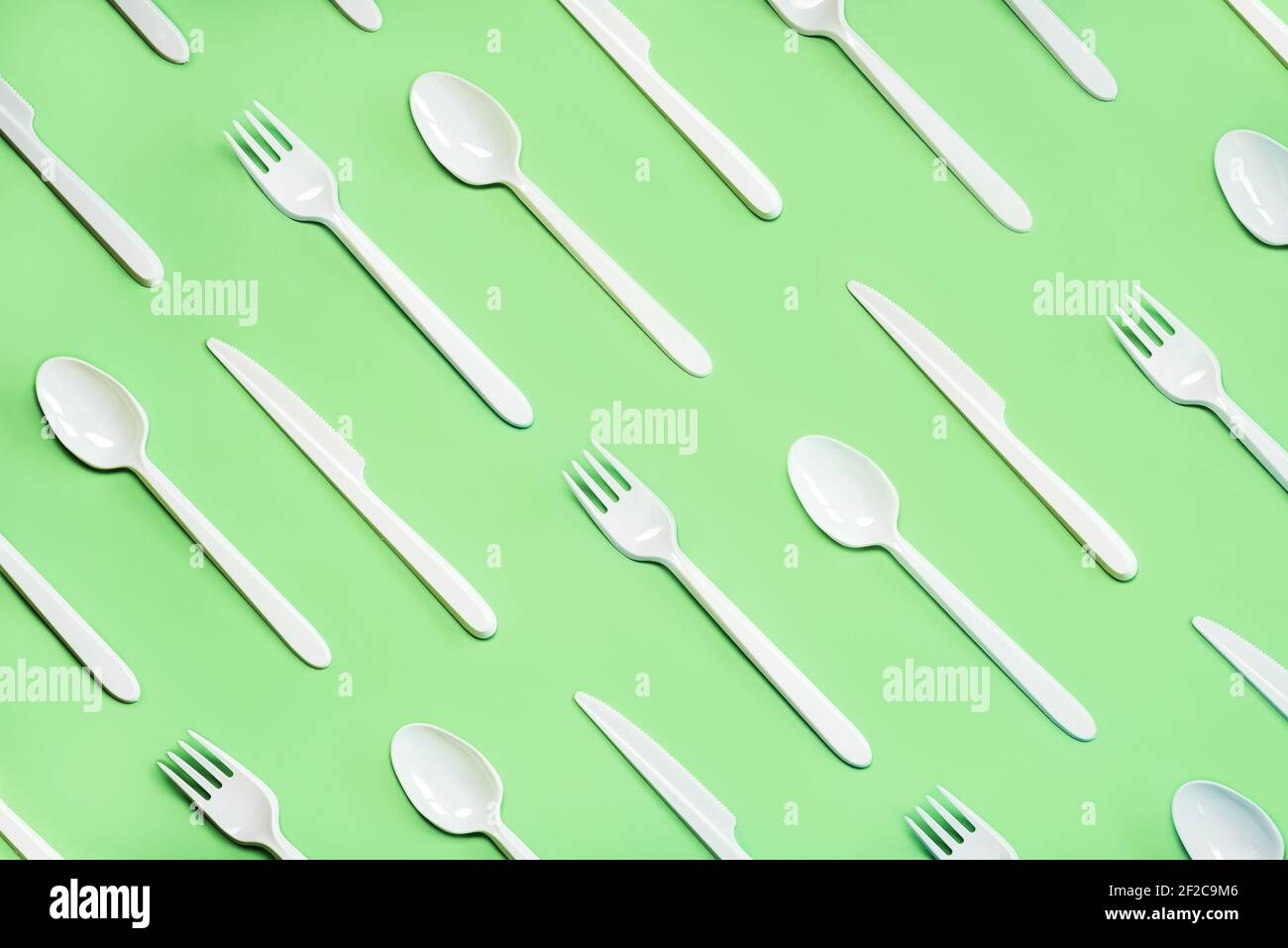 Geometric pattern made with white plastic cutlery on a green background Stock Photo