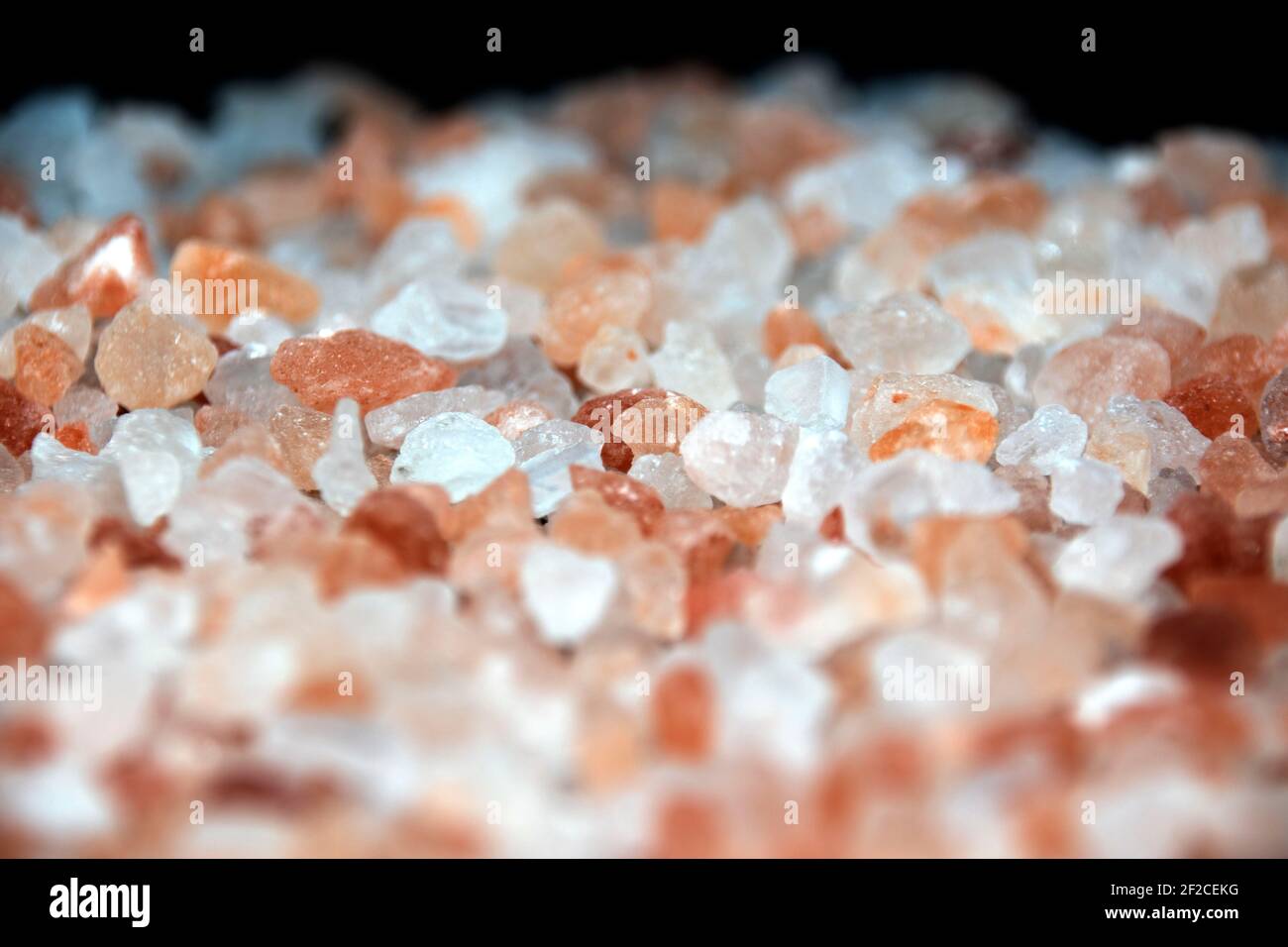 Large crystals of pink sea salt on a black background. Stock Photo