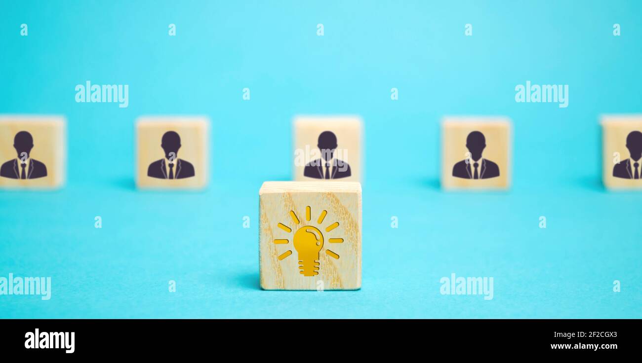 Wooden block with an idea light bulb icon and a team of workers. A collective innovate idea concept. Cooperation, teamwork. Strength in unity. Achievi Stock Photo
