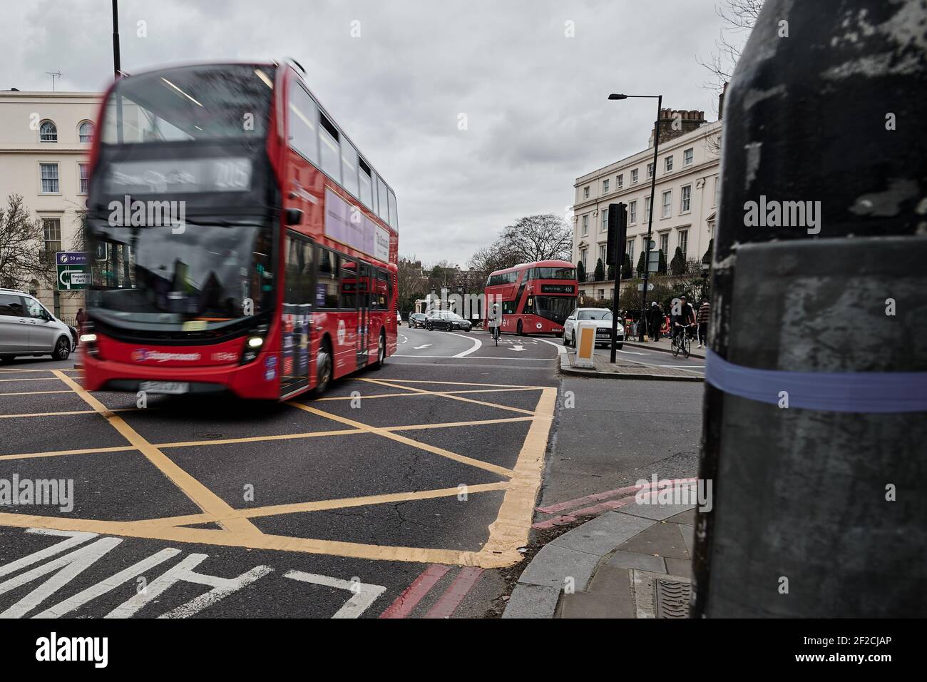 LondonUK - 6 Mar 2021: Motion Blurred image of modern red london double decker bus passing through a busy traffic junction over yellow hashed box Stock Photo