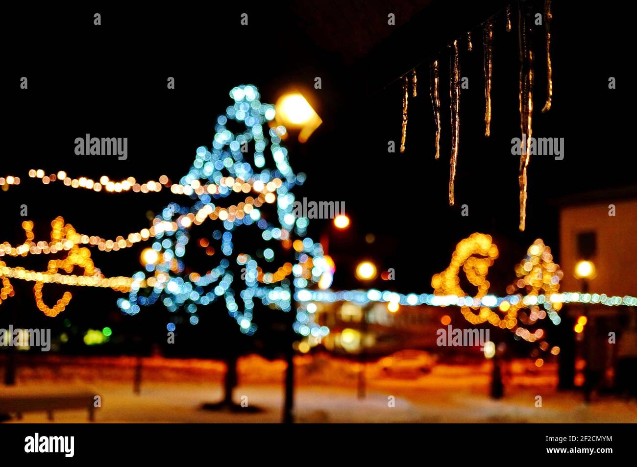 Picture of hanging icicles at night with blurred Christmas decoration in the background Stock Photo