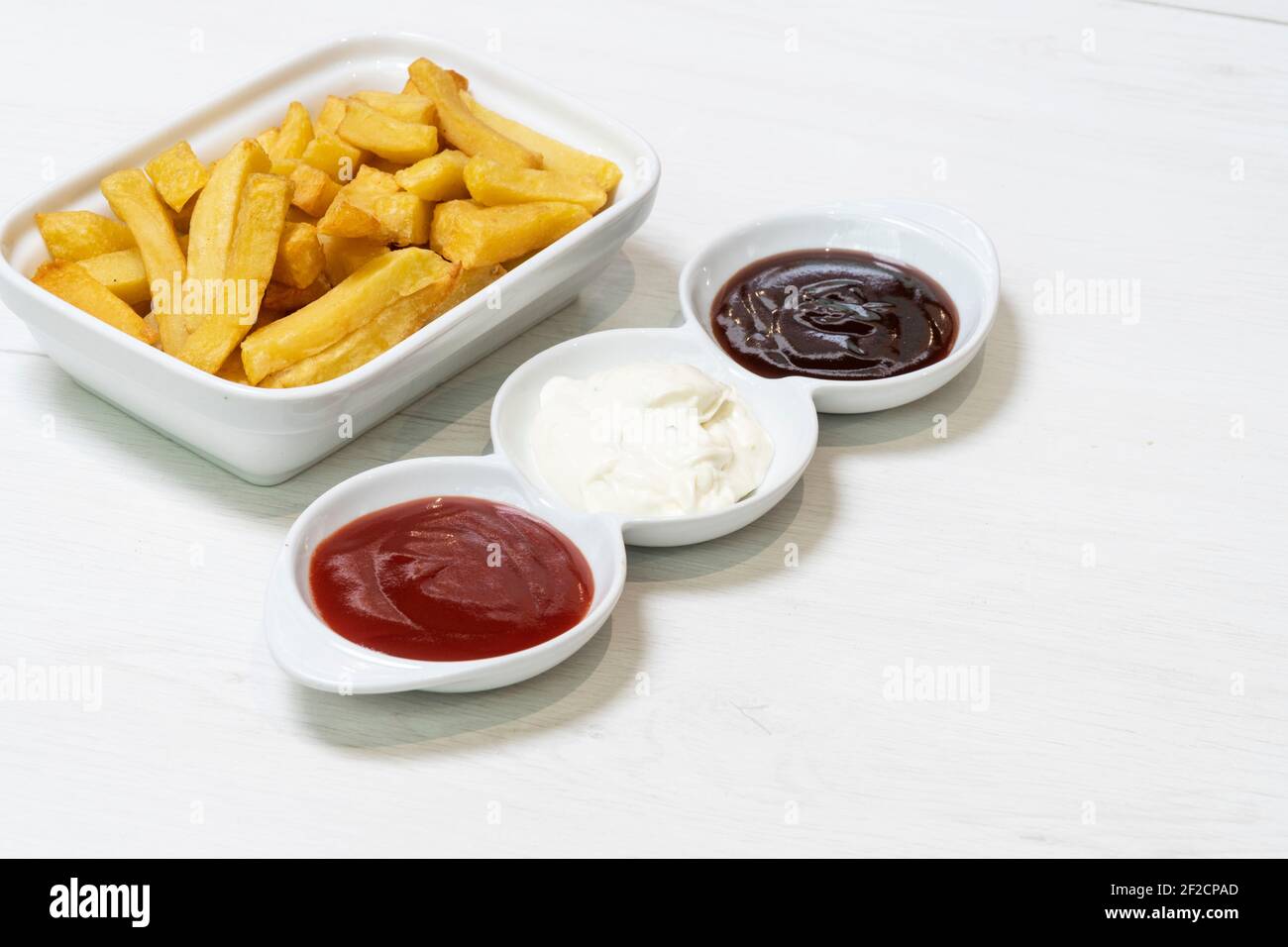 French fries with three dips, barbecue, mayo and ketchup on a table in