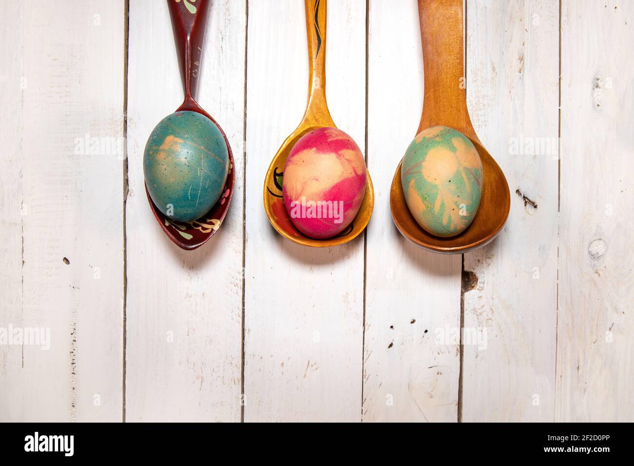 Flat lay with Easter eggs and spoons. Three wooden spoons with natural colored eggs on a white shabby chic background. Stock Photo