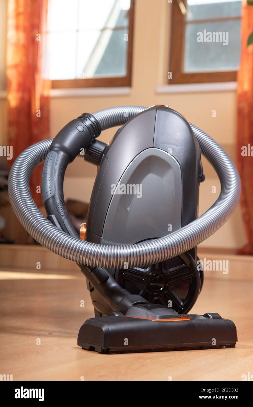 The Vacuum Cleaner on a laminate floor at room with windows on