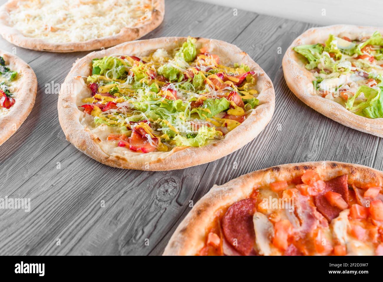 Assortment of pizza with meat, salami, prosciutto, tomatoes, dorblu mozzarella, parmesan, salad, fish on wooden boards. Four Stock Photo - Alamy