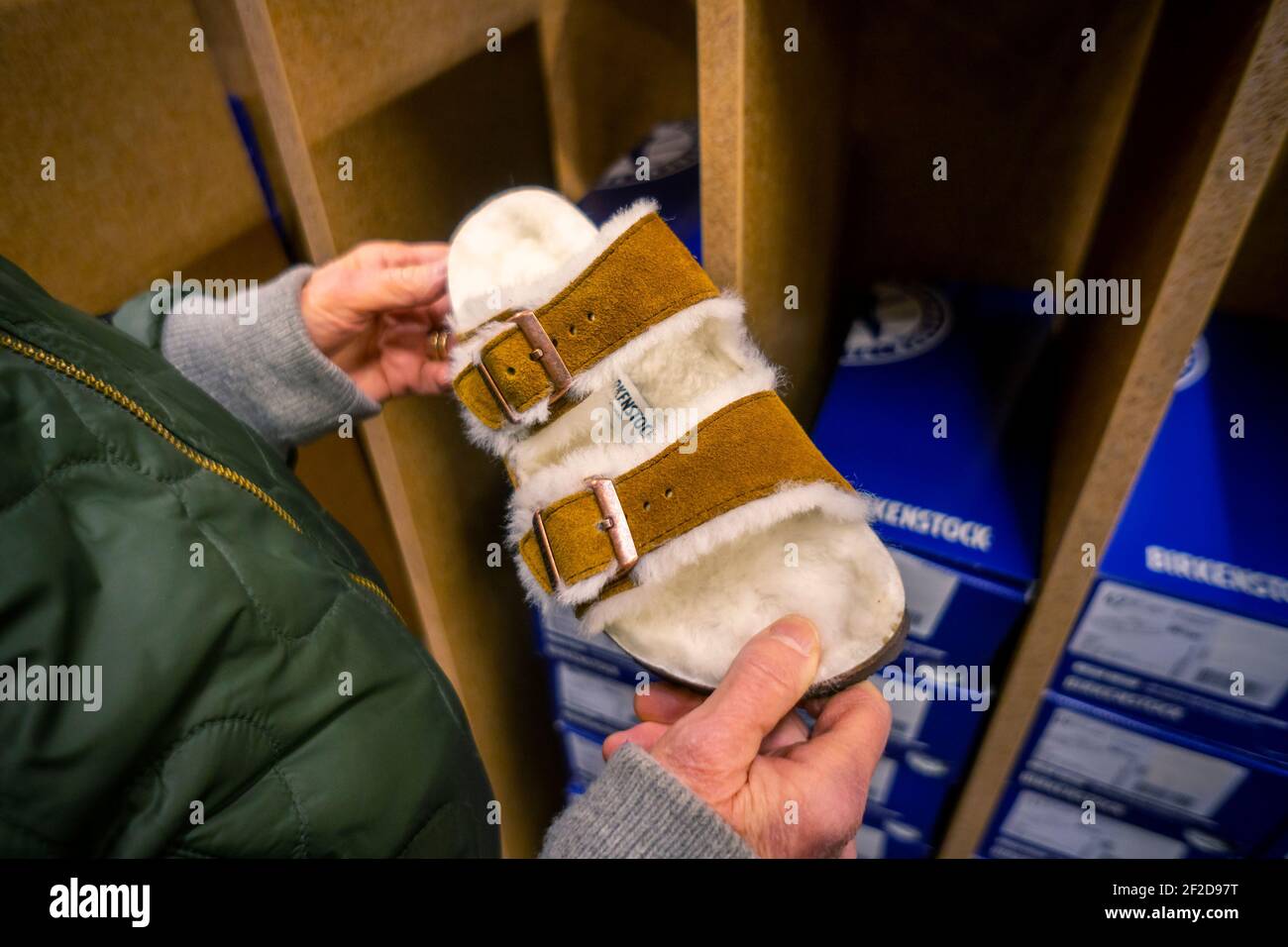 A shopper peruses the Birkenstock sandals displayed in a shoe store in New York on Friday, February 26, 2021. The French luxury brand LVMH has purchased a majority stake in the German sandal cobbler Birkenstock in a deal worth €4bn. (© Richard B. Levine) Stock Photo