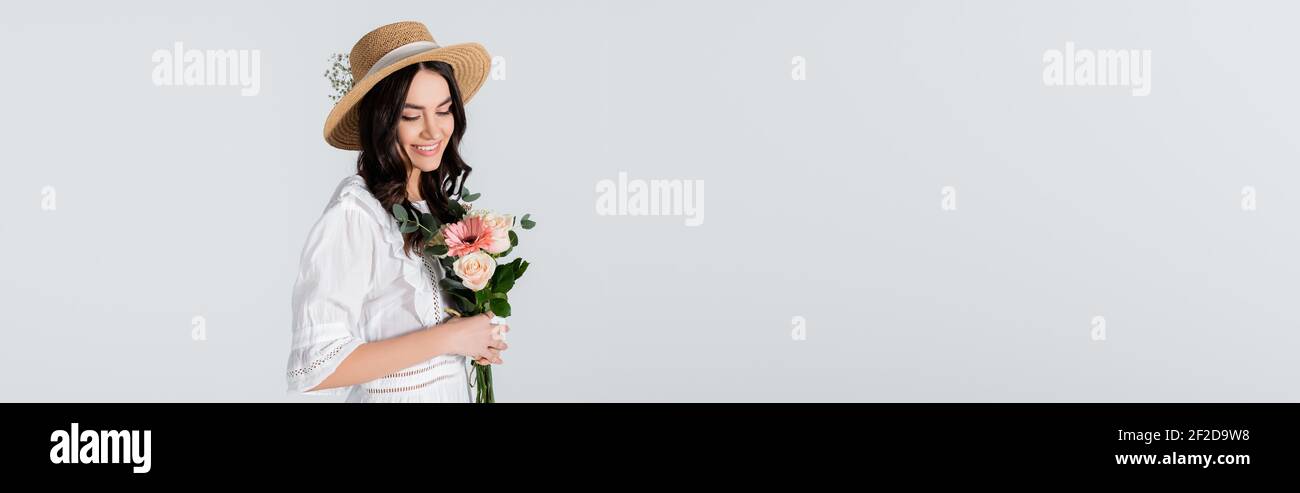 happy young woman in straw hat and dress holding bouquet of spring ...