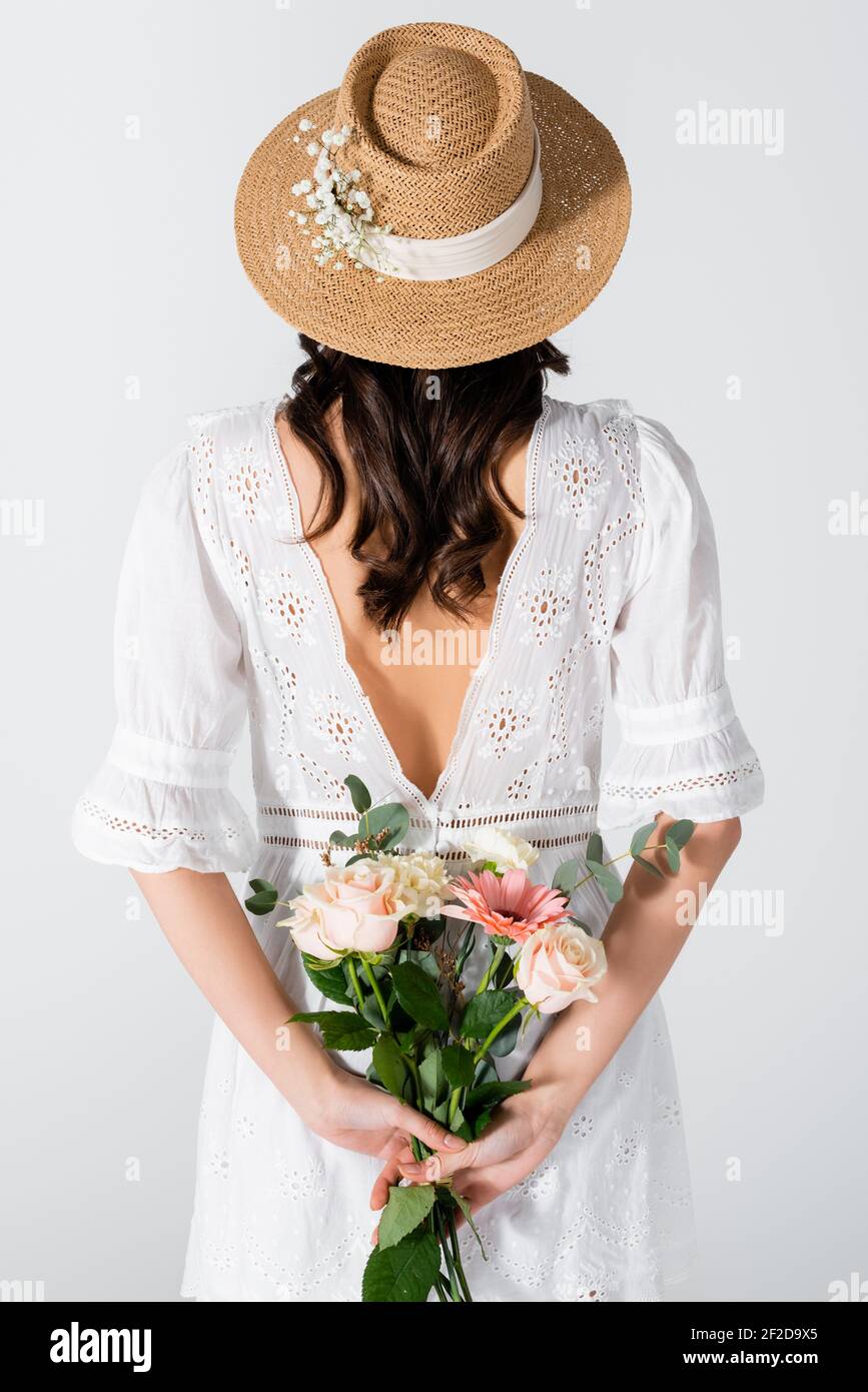 back view of woman in straw hat and dress holding bouquet isolated on ...